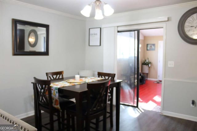 dining space featuring dark hardwood / wood-style floors, ornamental molding, and a notable chandelier