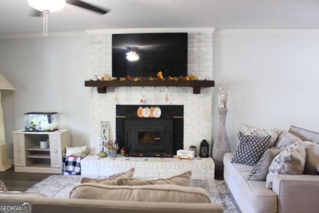 living room featuring wood-type flooring, a brick fireplace, ceiling fan, and ornamental molding