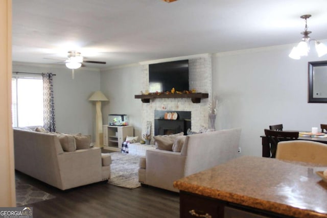 living room with dark hardwood / wood-style floors, crown molding, ceiling fan with notable chandelier, and a brick fireplace