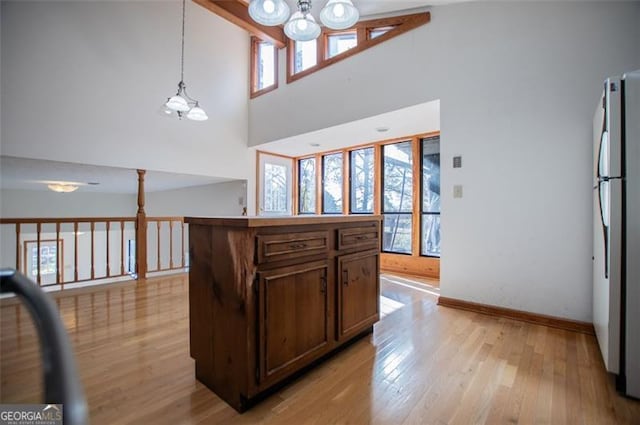 kitchen featuring a kitchen island, stainless steel refrigerator, high vaulted ceiling, and an inviting chandelier