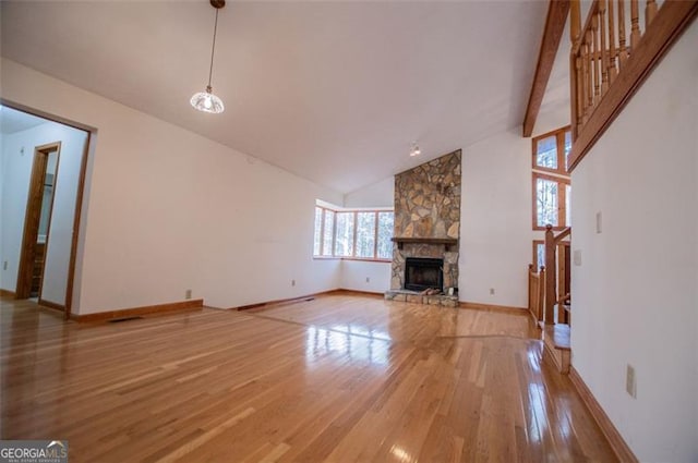 unfurnished living room featuring a stone fireplace, hardwood / wood-style floors, high vaulted ceiling, and beamed ceiling