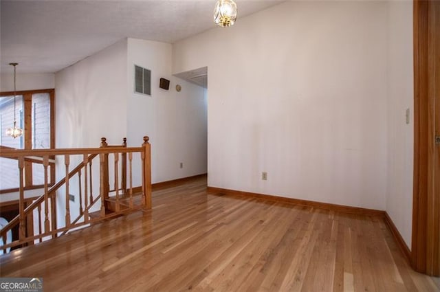 spare room featuring hardwood / wood-style floors and an inviting chandelier