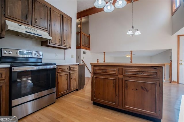 kitchen with electric range, light hardwood / wood-style flooring, a towering ceiling, a chandelier, and decorative light fixtures