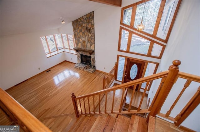 stairway with hardwood / wood-style floors, a fireplace, and high vaulted ceiling