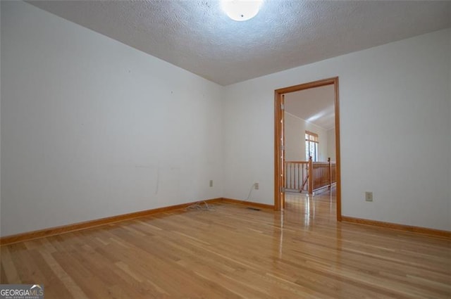 unfurnished room featuring a textured ceiling and light wood-type flooring