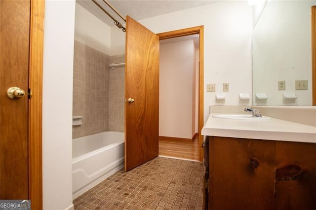 bathroom with vanity, hardwood / wood-style flooring, and tiled shower / bath