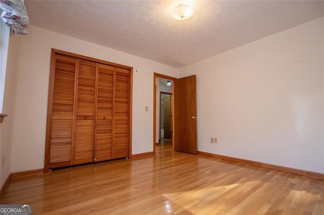 unfurnished bedroom featuring light hardwood / wood-style floors, a textured ceiling, and a closet