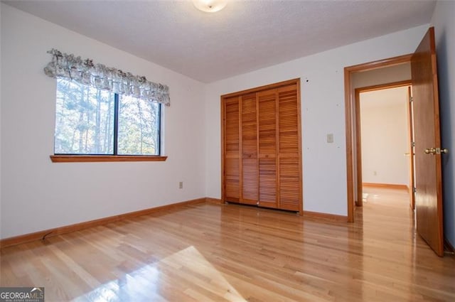 unfurnished bedroom with a closet, light hardwood / wood-style floors, and a textured ceiling