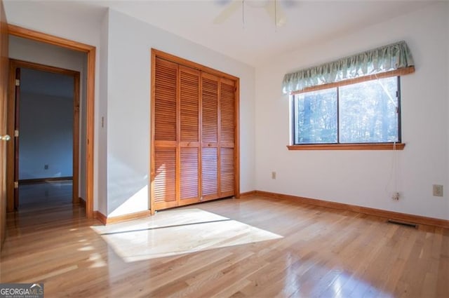 unfurnished bedroom featuring light hardwood / wood-style flooring, a closet, and ceiling fan