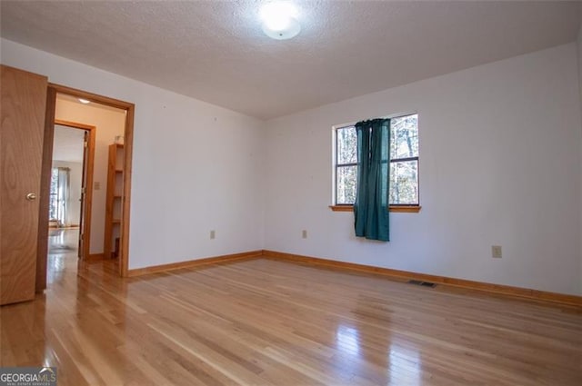 spare room featuring a textured ceiling and light hardwood / wood-style flooring