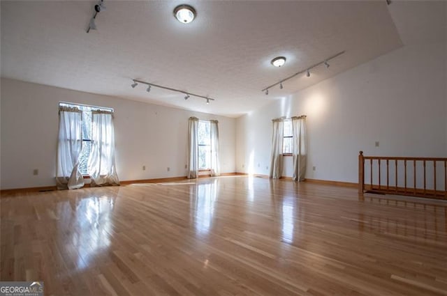 spare room featuring a textured ceiling, rail lighting, and light hardwood / wood-style flooring