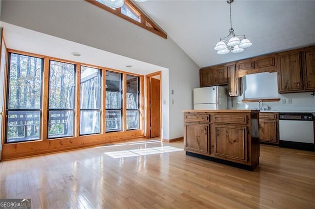 kitchen featuring dishwasher, an inviting chandelier, white refrigerator, hanging light fixtures, and light hardwood / wood-style flooring