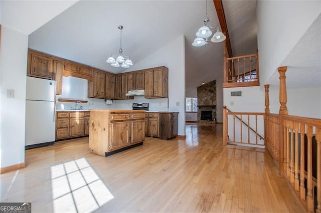 kitchen with an inviting chandelier, white fridge, light hardwood / wood-style floors, pendant lighting, and a fireplace