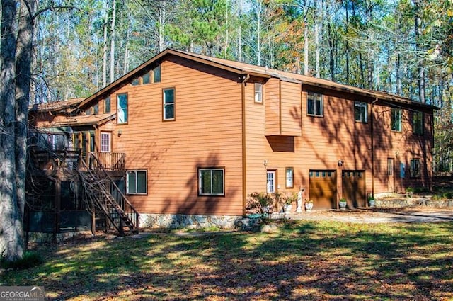 rear view of property featuring a garage, a deck, and a yard