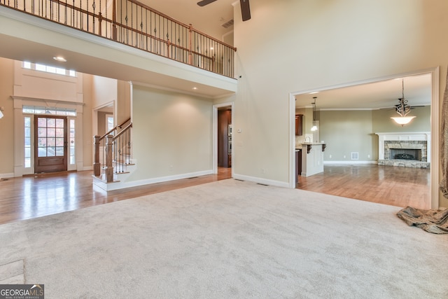 unfurnished living room with light hardwood / wood-style flooring, a high ceiling, and ornamental molding