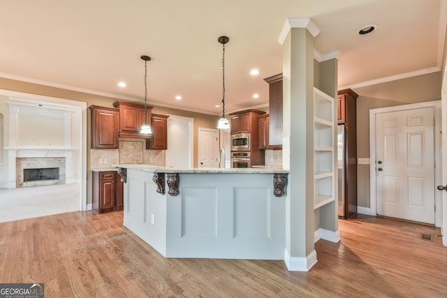 kitchen featuring hanging light fixtures, stainless steel appliances, backsplash, a breakfast bar area, and ornamental molding