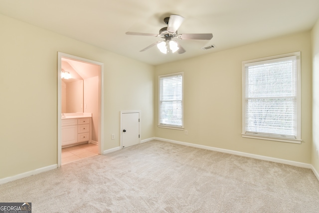 unfurnished bedroom featuring ensuite bathroom, ceiling fan, and light colored carpet