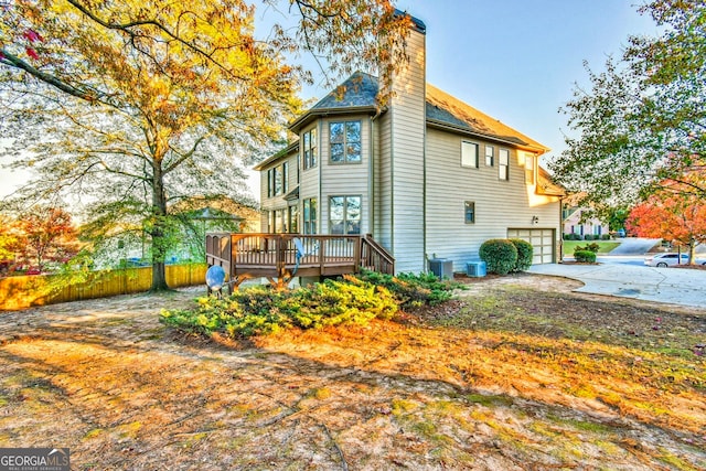 view of side of property featuring cooling unit, a garage, and a wooden deck