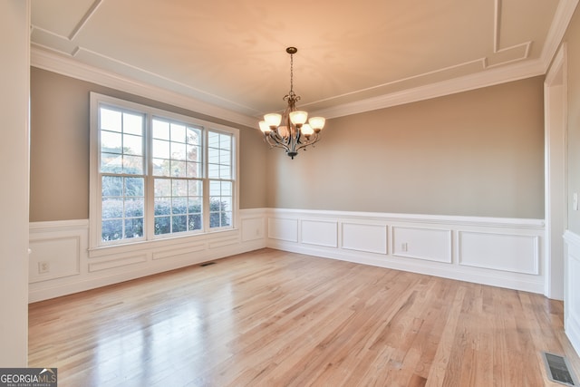 empty room with crown molding, light hardwood / wood-style floors, and a notable chandelier