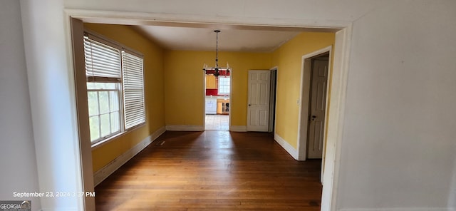 unfurnished dining area featuring a chandelier, dark hardwood / wood-style floors, and a healthy amount of sunlight