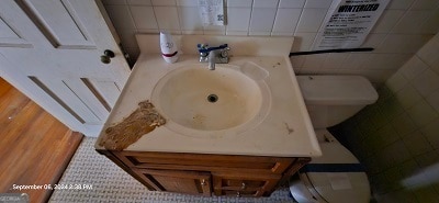 bathroom with tile patterned flooring, vanity, toilet, and tile walls