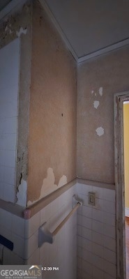 bathroom featuring crown molding and tile walls