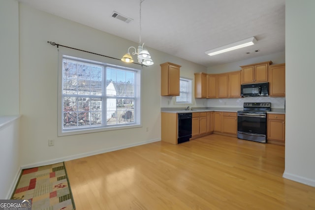 kitchen with tasteful backsplash, decorative light fixtures, a chandelier, light hardwood / wood-style floors, and black appliances