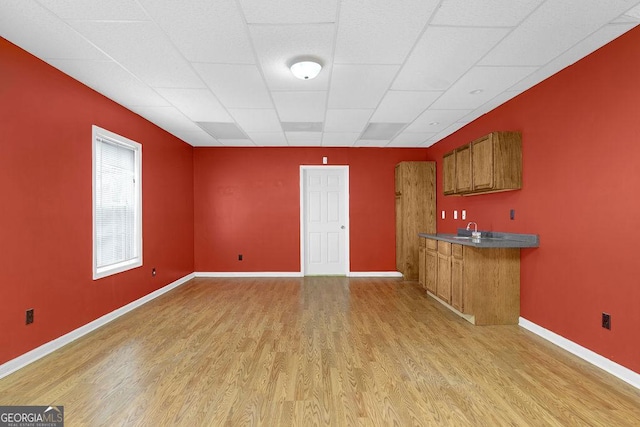 kitchen featuring a drop ceiling, sink, and light hardwood / wood-style floors