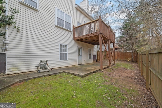 rear view of house featuring a wooden deck, a patio area, and a lawn