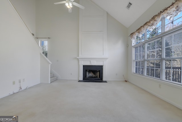 unfurnished living room featuring high vaulted ceiling, light carpet, ceiling fan, a healthy amount of sunlight, and a fireplace