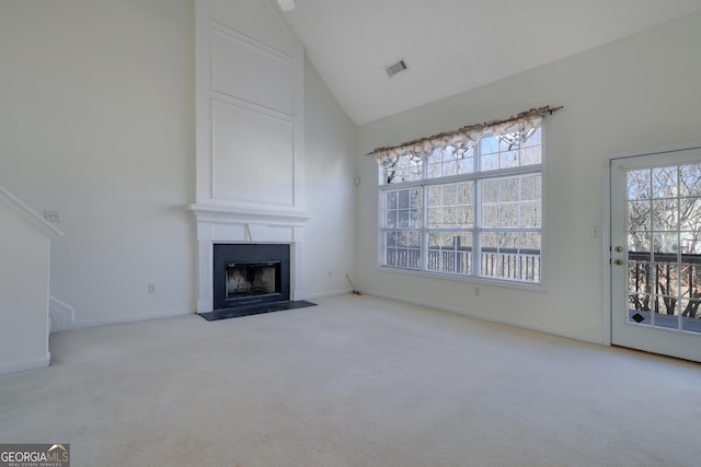 unfurnished living room with a large fireplace, high vaulted ceiling, and light colored carpet