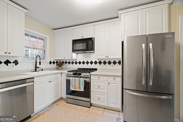 kitchen featuring white cabinets, sink, light tile patterned floors, tasteful backsplash, and stainless steel appliances