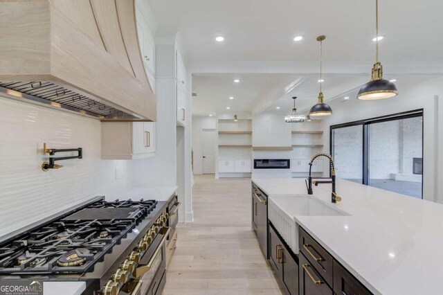 kitchen with pendant lighting, light wood-type flooring, dark brown cabinets, custom range hood, and stainless steel appliances