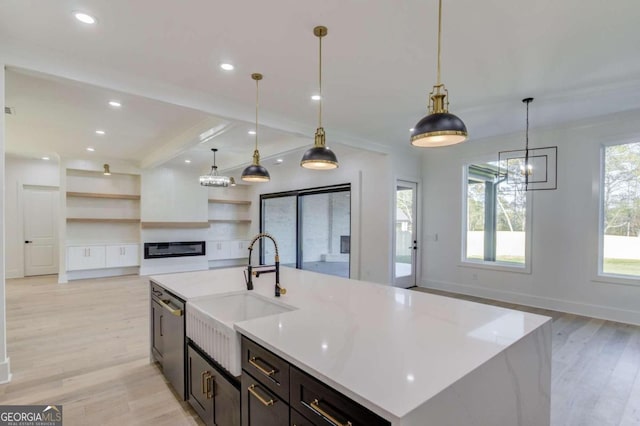 kitchen with sink, a center island with sink, pendant lighting, and light hardwood / wood-style flooring