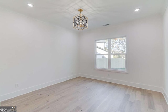 spare room featuring light hardwood / wood-style floors and a notable chandelier