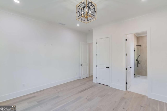 unfurnished bedroom with light hardwood / wood-style floors, connected bathroom, and a chandelier