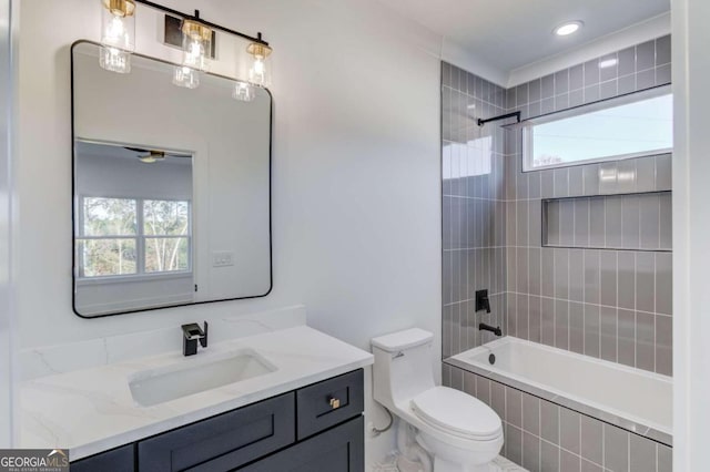 full bathroom featuring vanity, tiled shower / bath combo, toilet, and a healthy amount of sunlight