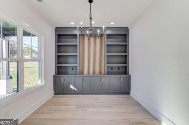 unfurnished office with plenty of natural light, an inviting chandelier, and light wood-type flooring