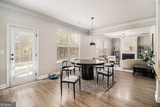 dining area featuring a wealth of natural light, ornamental molding, and hardwood / wood-style flooring