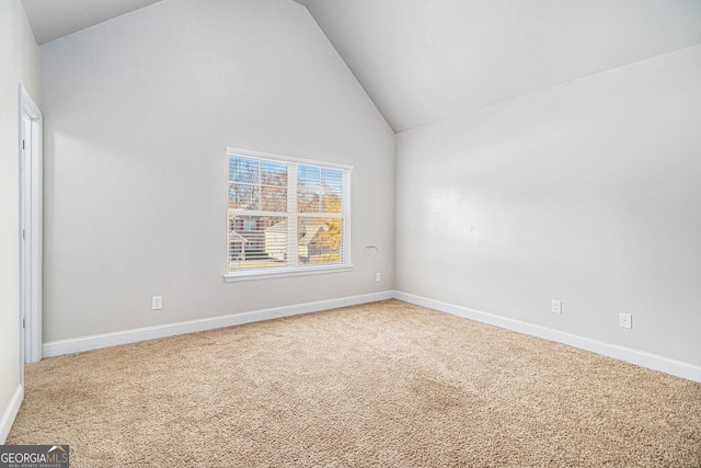 carpeted empty room with high vaulted ceiling