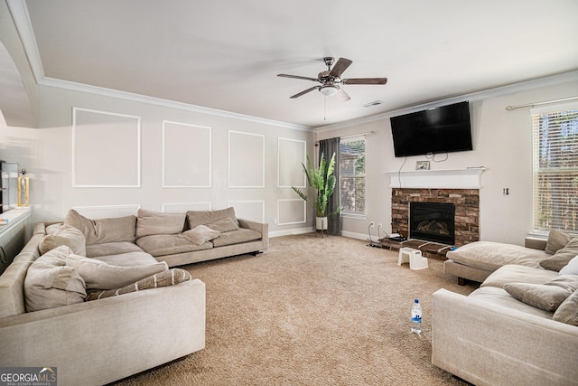 living room with carpet flooring, a stone fireplace, ceiling fan, and ornamental molding