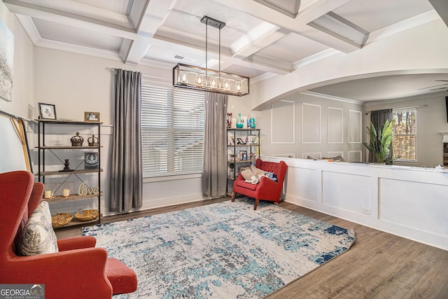 sitting room featuring wood-type flooring, ornamental molding, coffered ceiling, and beam ceiling