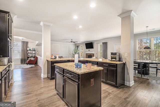 kitchen featuring ceiling fan, crown molding, decorative light fixtures, light hardwood / wood-style flooring, and a kitchen island