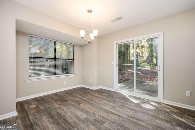 empty room featuring dark hardwood / wood-style flooring and an inviting chandelier