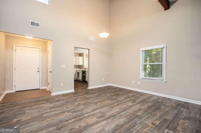 unfurnished room with a towering ceiling and dark wood-type flooring