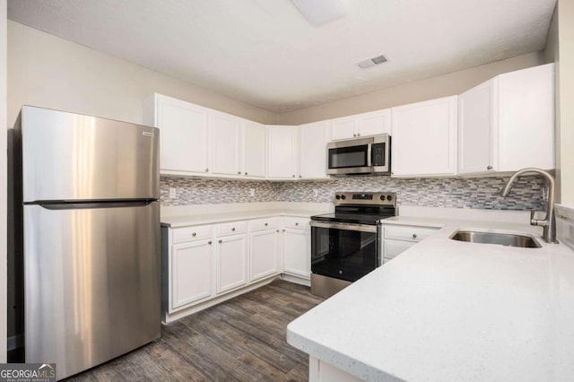 kitchen with backsplash, dark wood-type flooring, white cabinets, sink, and stainless steel appliances