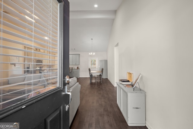 hallway featuring a notable chandelier, lofted ceiling, and dark wood-type flooring