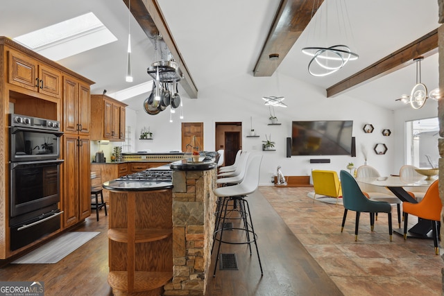 kitchen featuring double oven, lofted ceiling with skylight, a breakfast bar area, and dark wood-type flooring