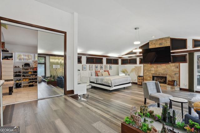 bedroom featuring a fireplace, hardwood / wood-style flooring, and vaulted ceiling