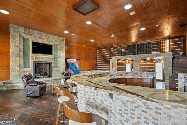 bar featuring dark parquet floors, a stone fireplace, and wood ceiling